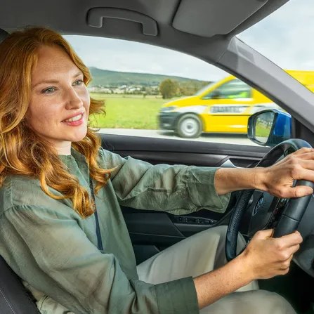 Fahrerin in einem Auto, im Hintergrund ein ÖAMTC Fahrzeug